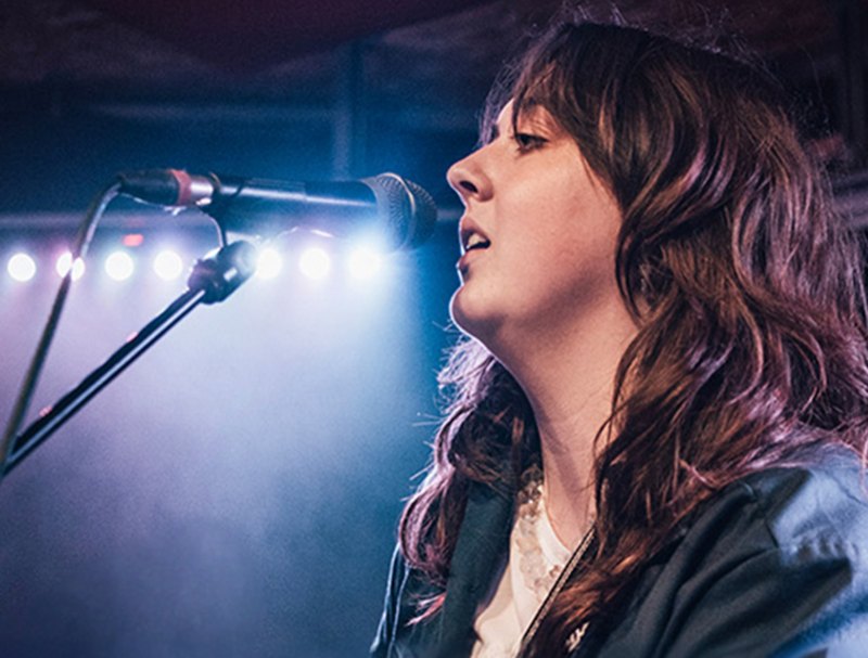 A singer performing into a microphone under stage lights.