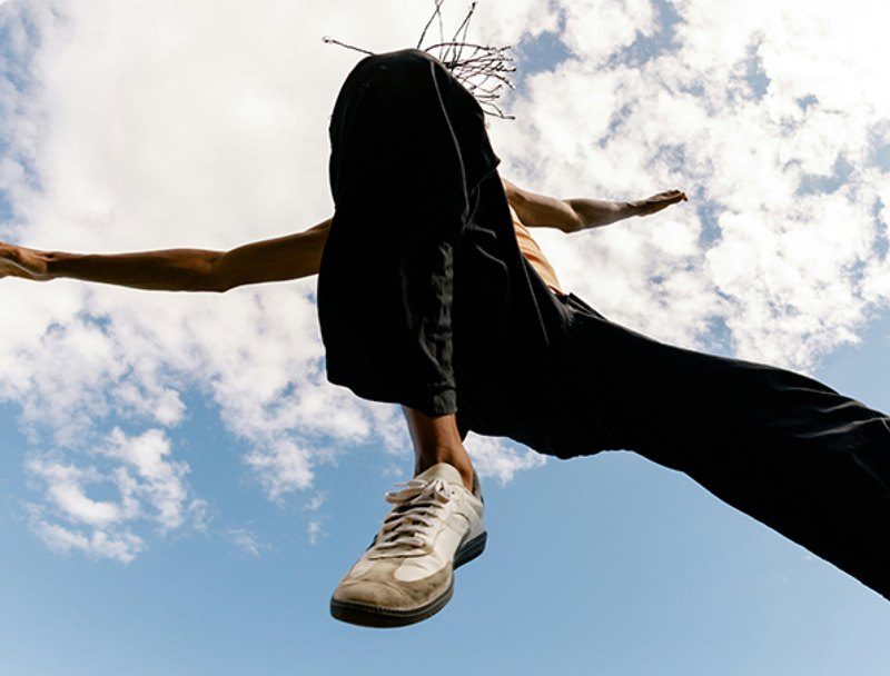 A skateboarder mid-jump against a bright blue sky.