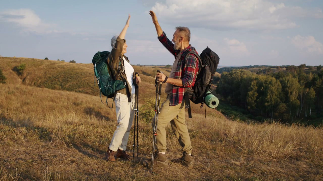Senior Hikers High-Fiving on Hilltop