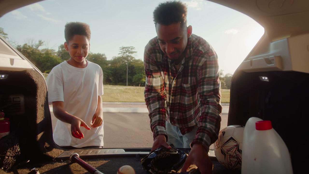 Father and Son Getting Baseball Gear From Car Trunk