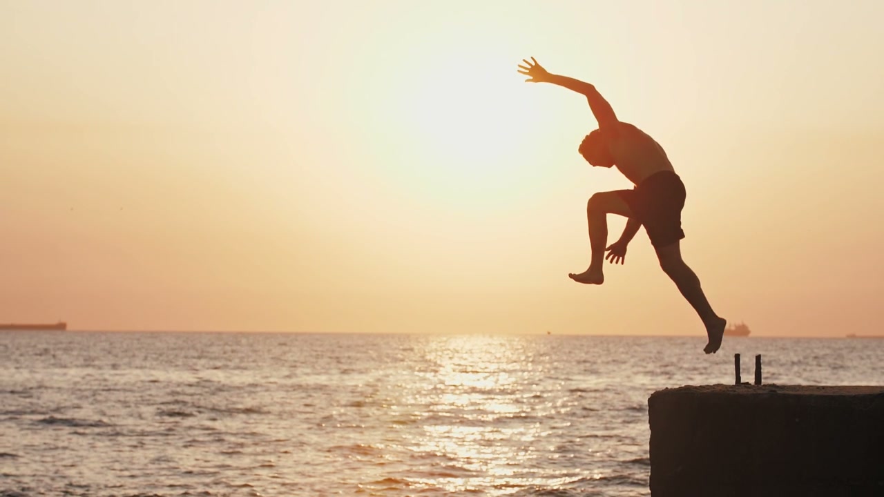 Man Doing Backflip into Ocean at Sunset