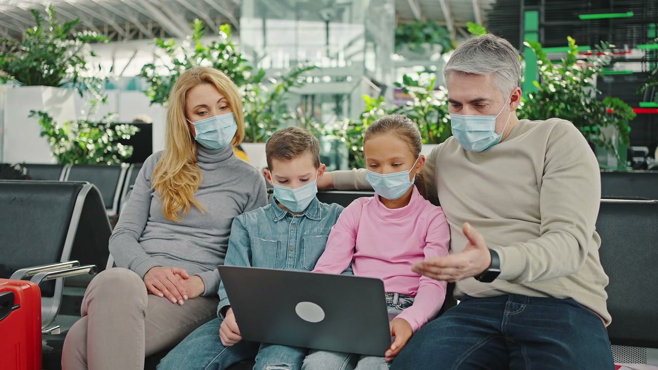 Family Wearing Masks on Laptop at Airport