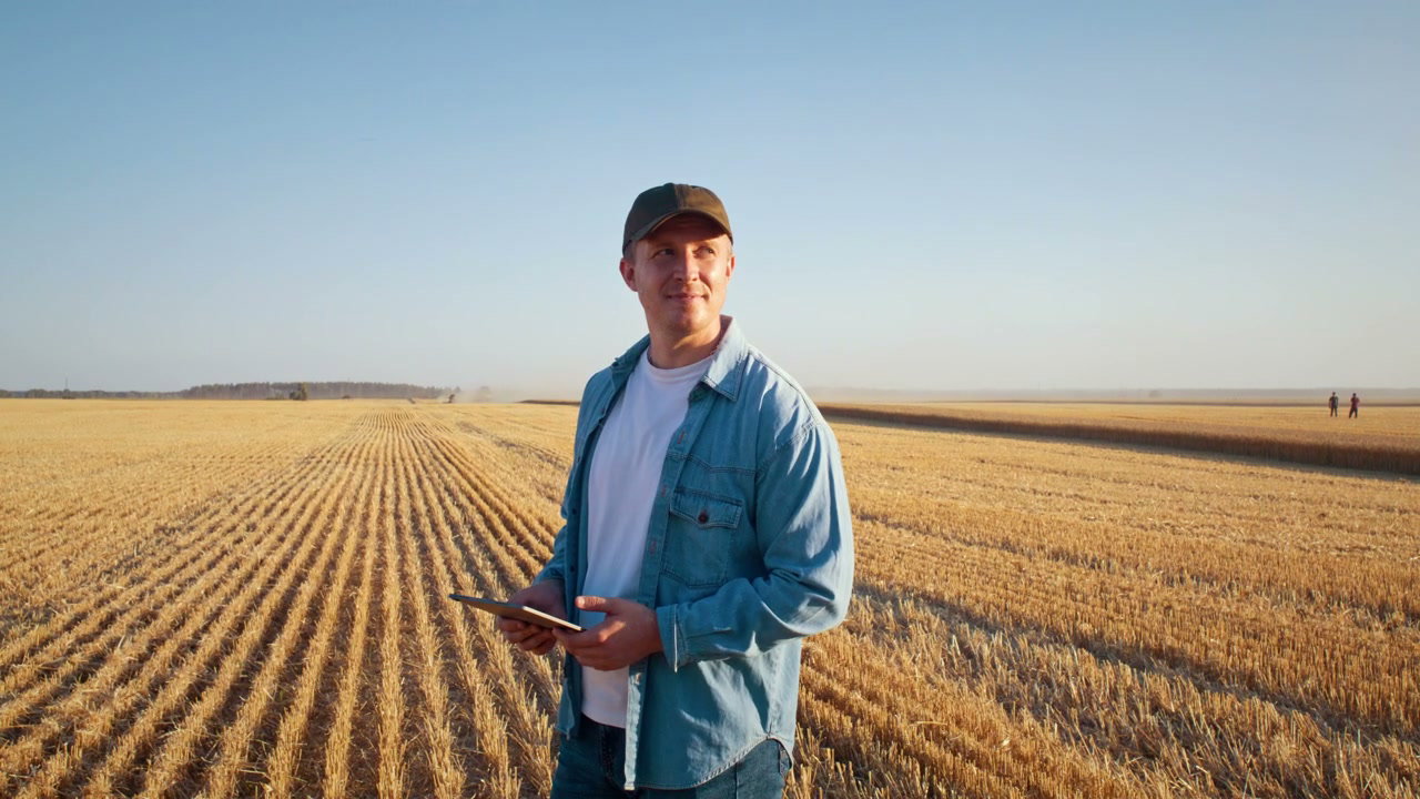 Farmer Holding Tablet in Harvested Field