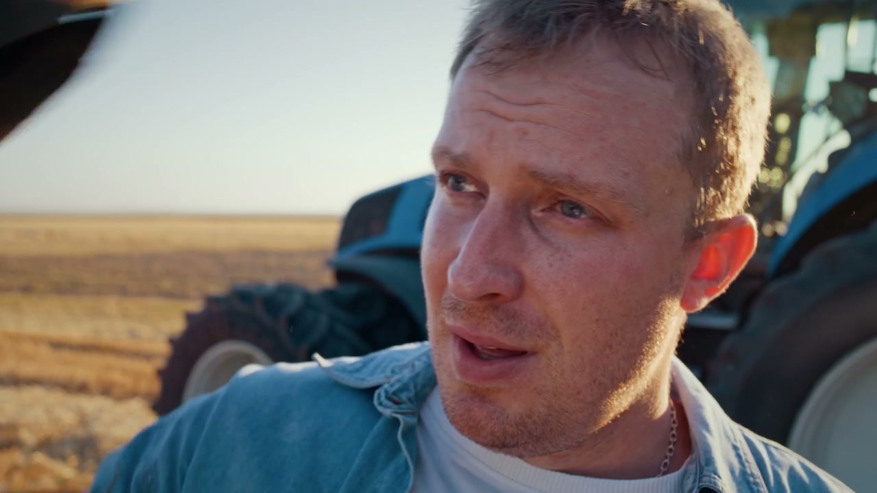 Farmer Shields Eyes From Sun in Field