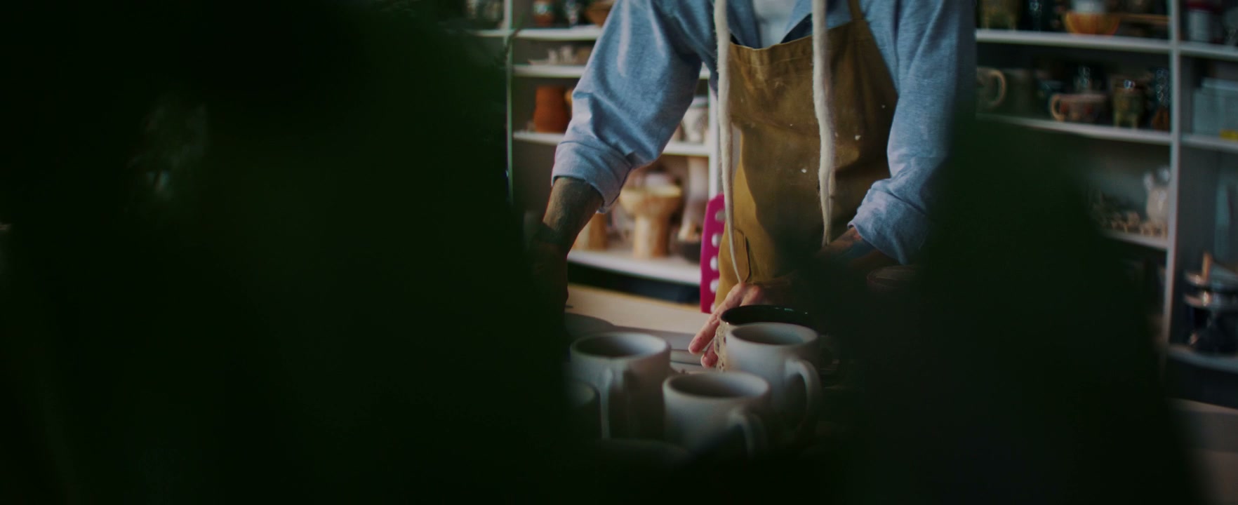 Artisan Arranging Ceramic Mugs in Studio