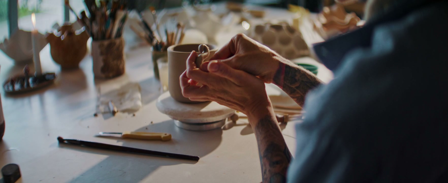 Pottery Artist Attaching Handle to Clay Mug