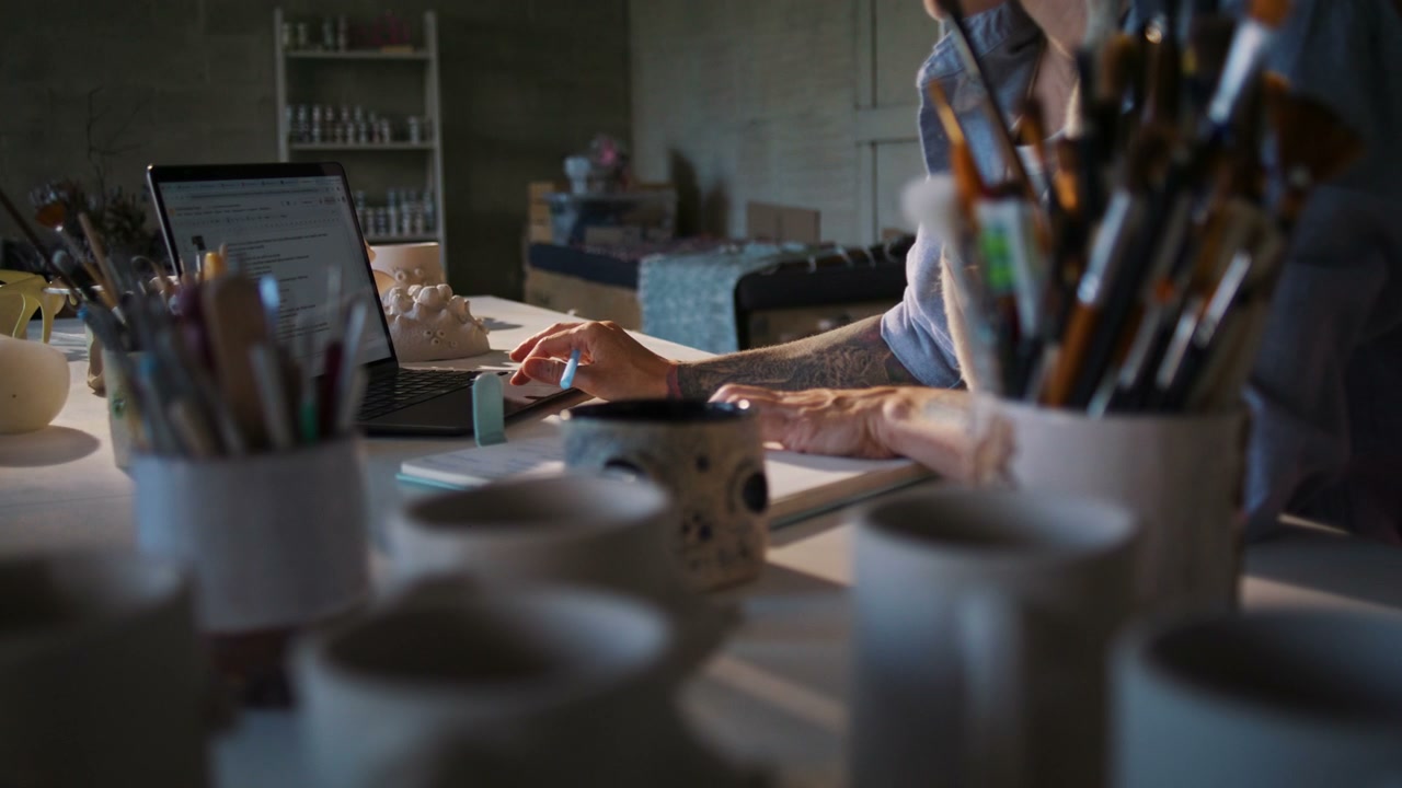 Person Working on Laptop in Ceramic Studio
