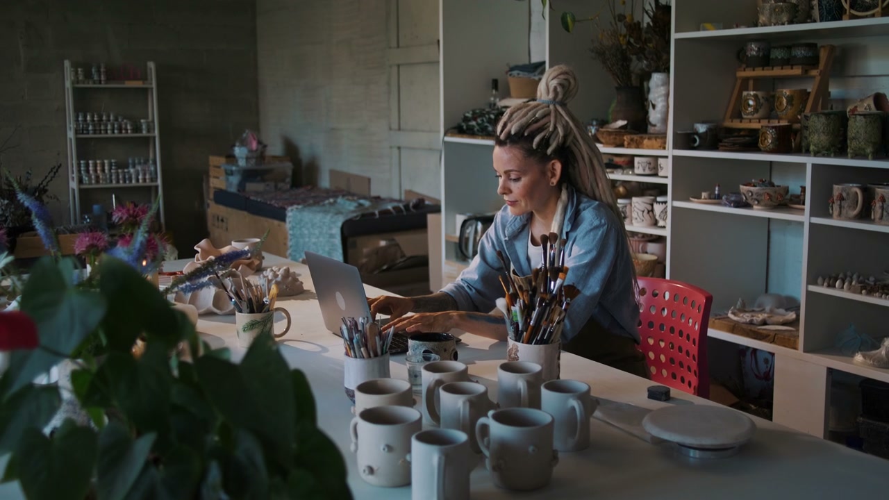 Woman Working on Laptop in Ceramic Studio