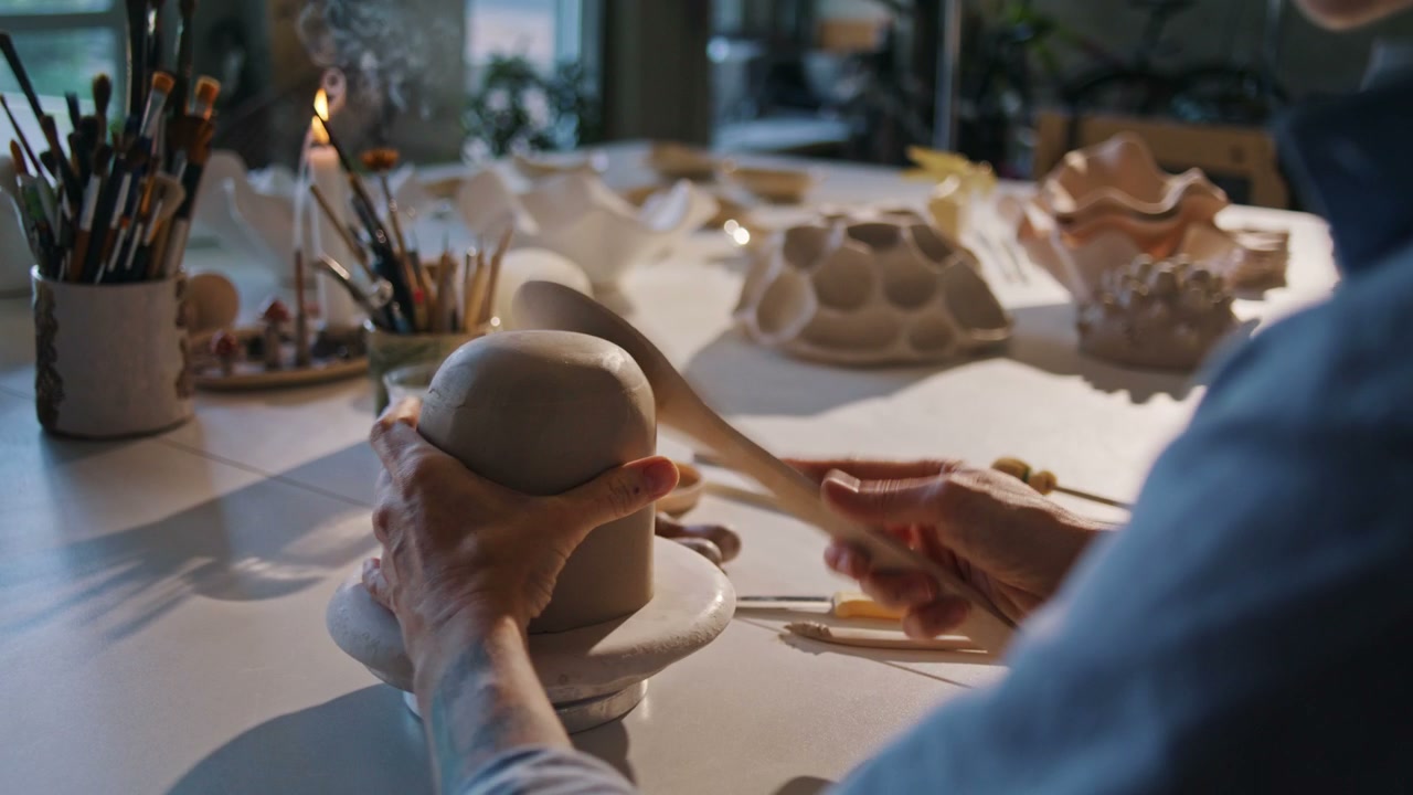 Craftsperson Shaping Clay in Studio