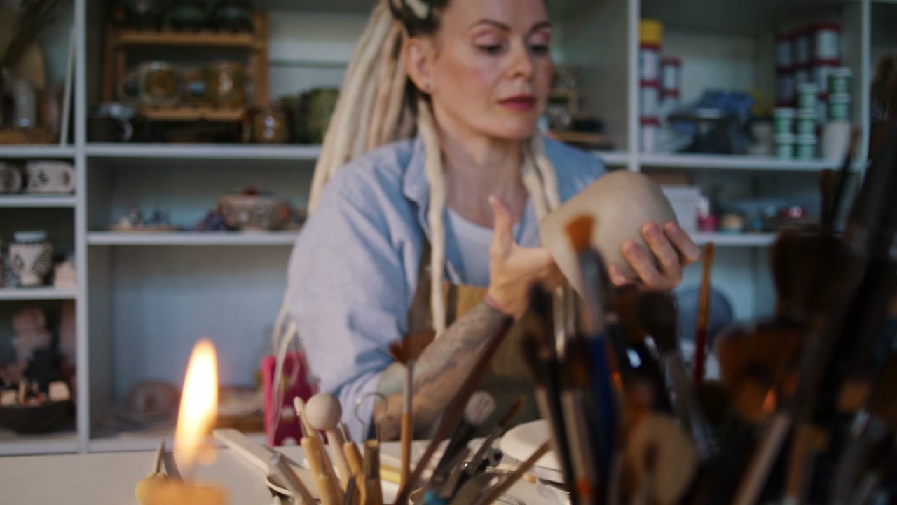 Artist Inspecting Clay Pot in Ceramic Studio