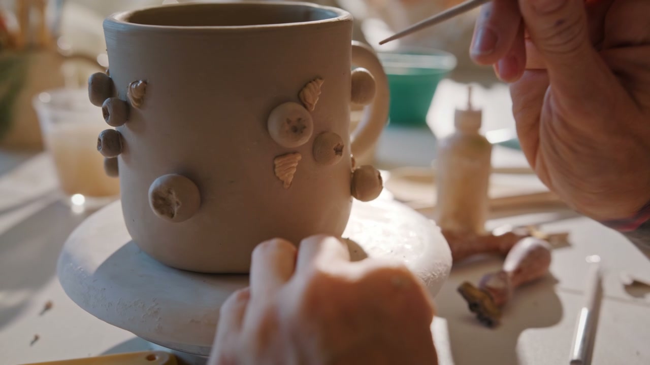 Hands Decorating Clay Mug with Berries