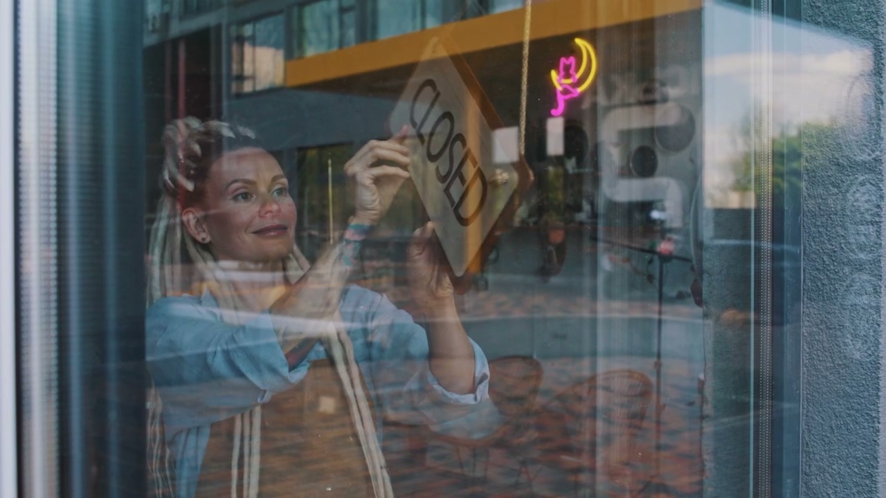 Woman Flipping Open Sign in Shop Window