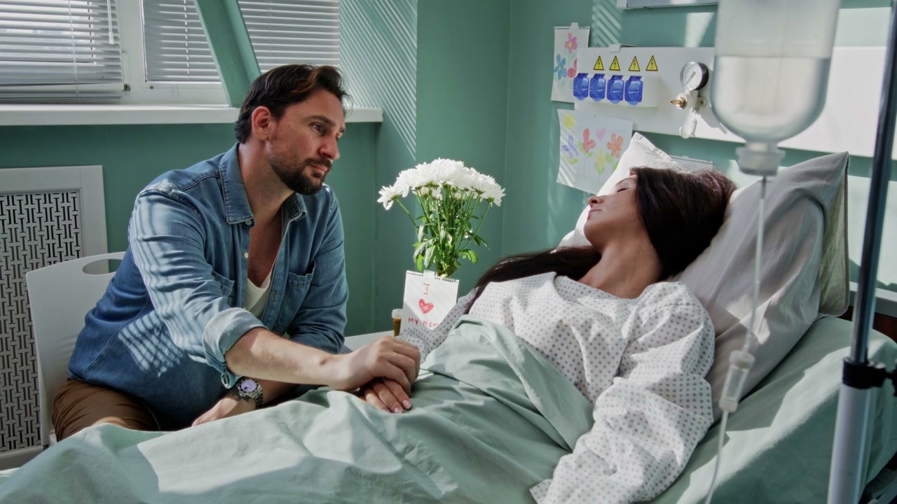 Man Comforts Woman in Hospital Bed