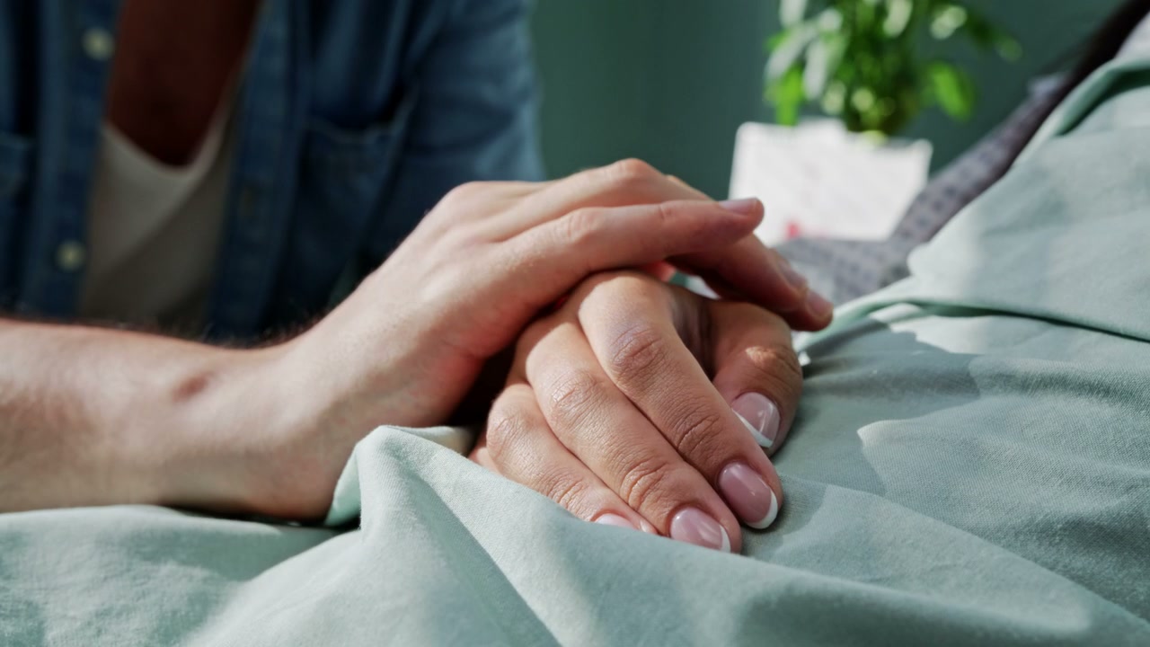 Caring Hands Holding on a Hospital Bed