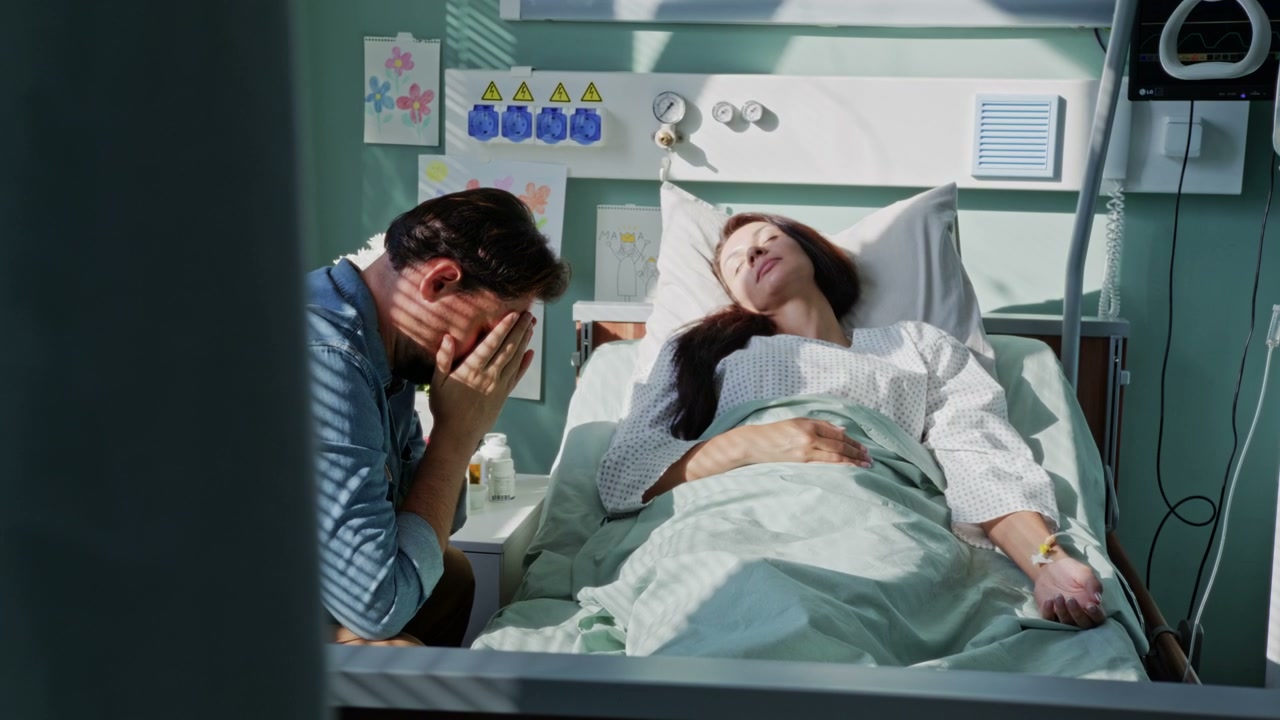 Man Comforting Woman in Hospital Bed