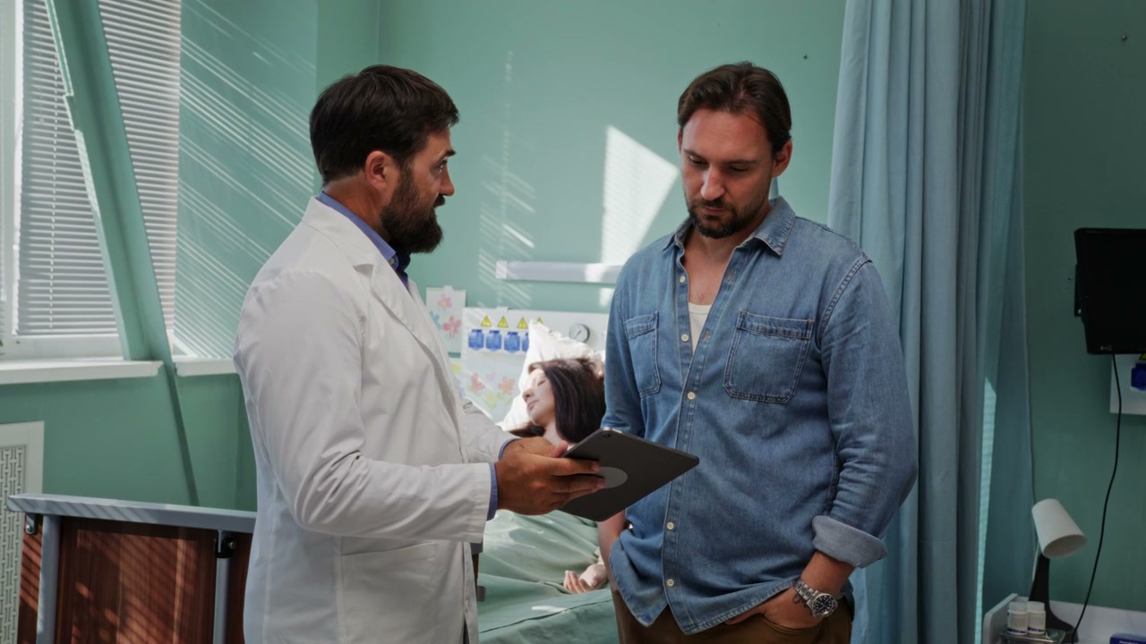 Doctor Discussing Patient with Man in Hospital