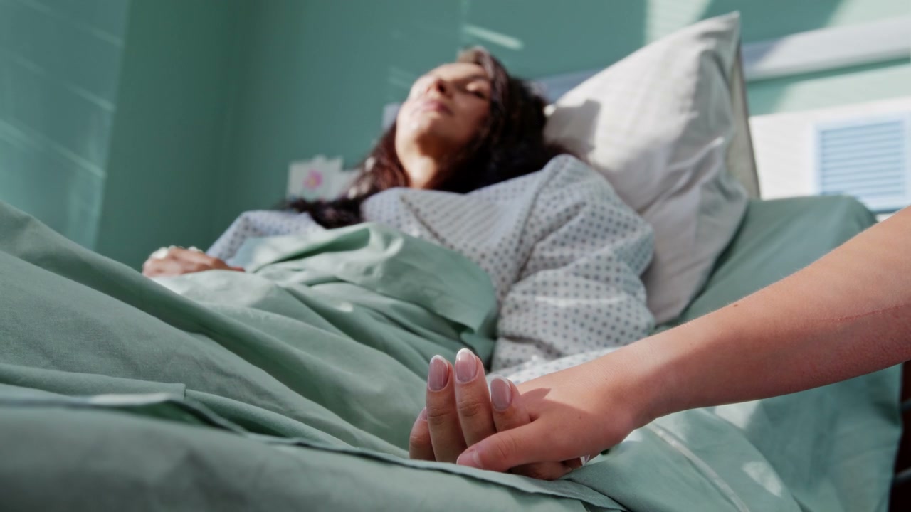 Child Holding Mother's Hand in Hospital Bed