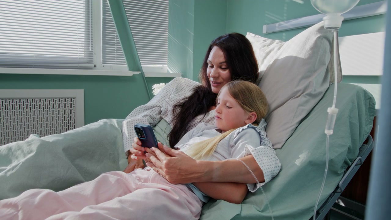 Mother and Child Using Smartphone in Hospital Bed