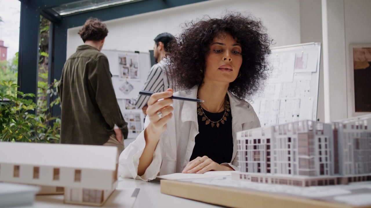 Architect Drawing And Examining Building Model