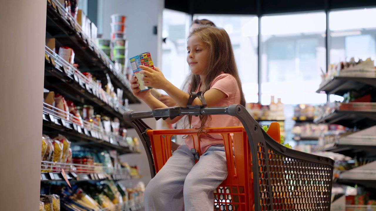 Girl Looking at Box in Supermarket Cart