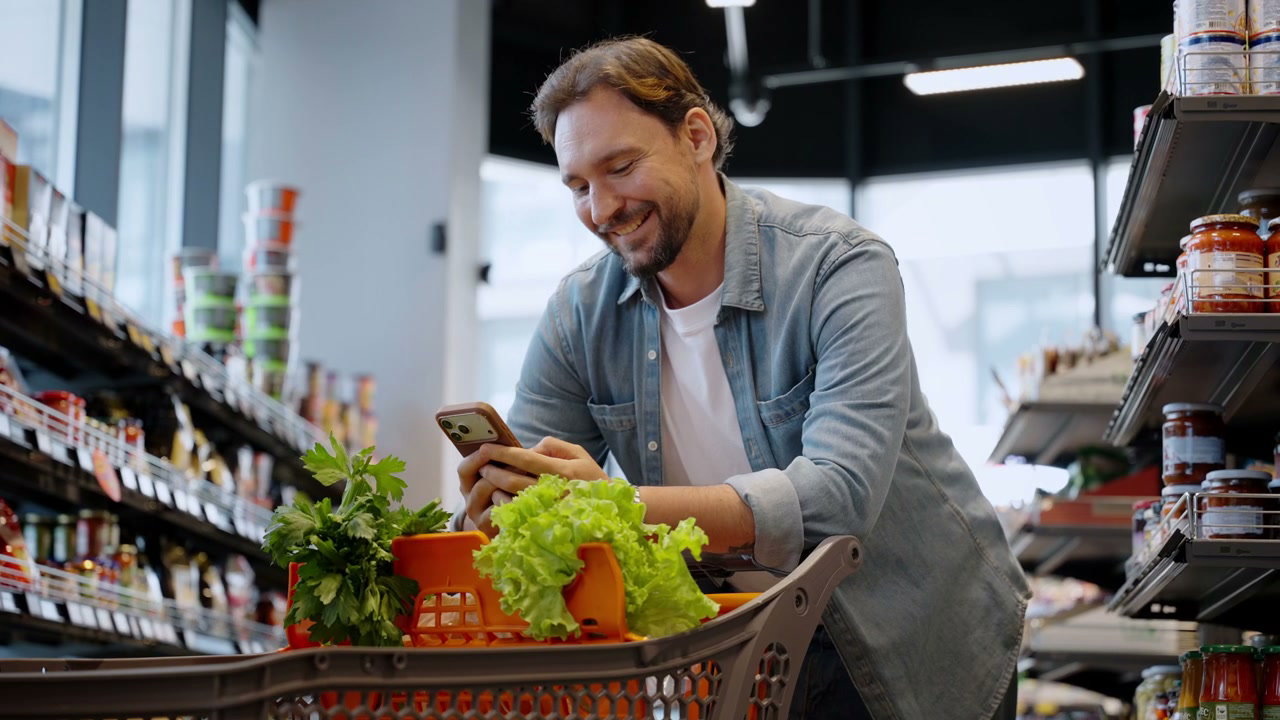 Man Using Phone in Grocery Store Aisle