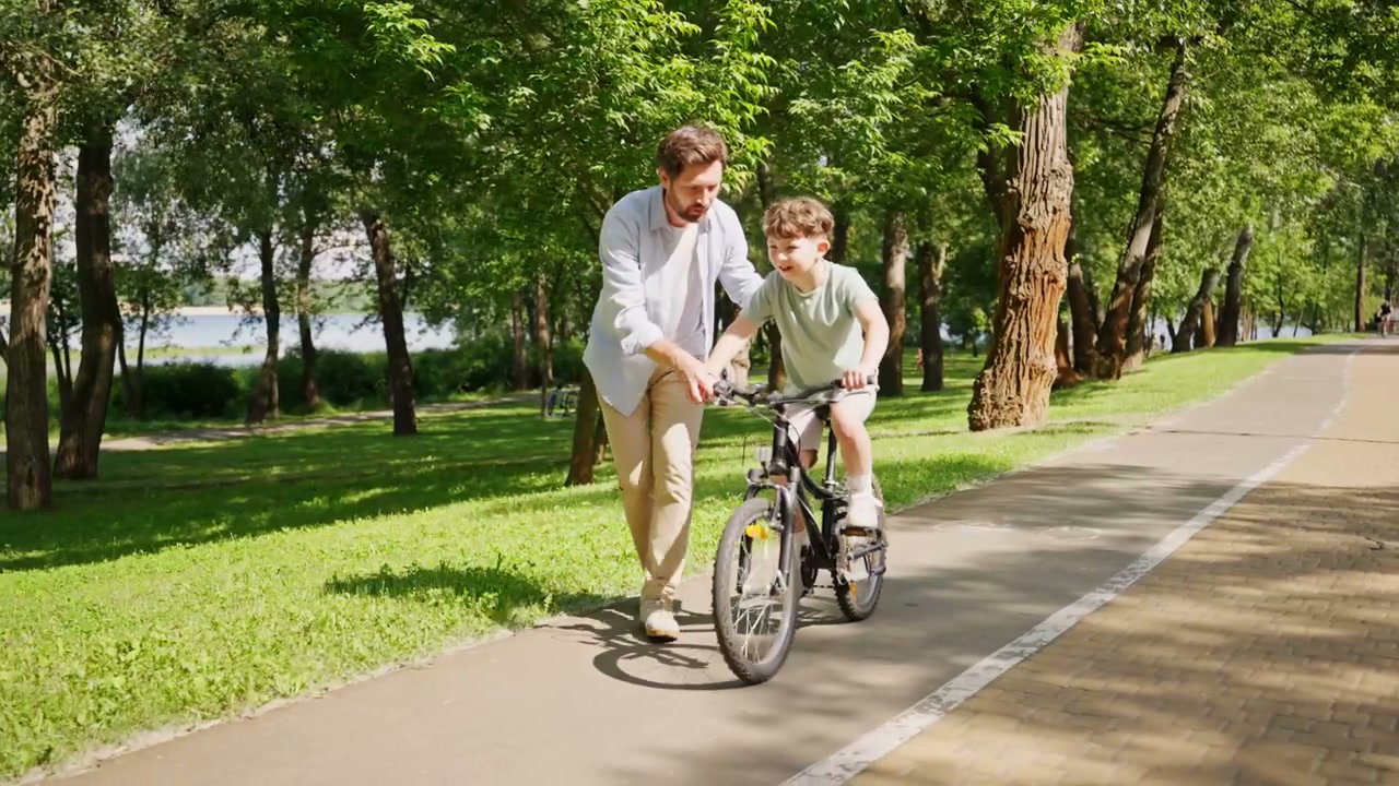 Father Teaches Son to Ride Bike in Park