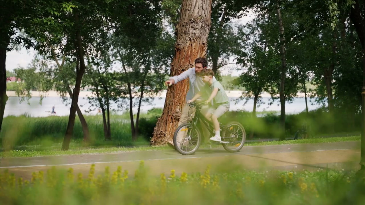 Father Teaches Son to Ride Bicycle in Park