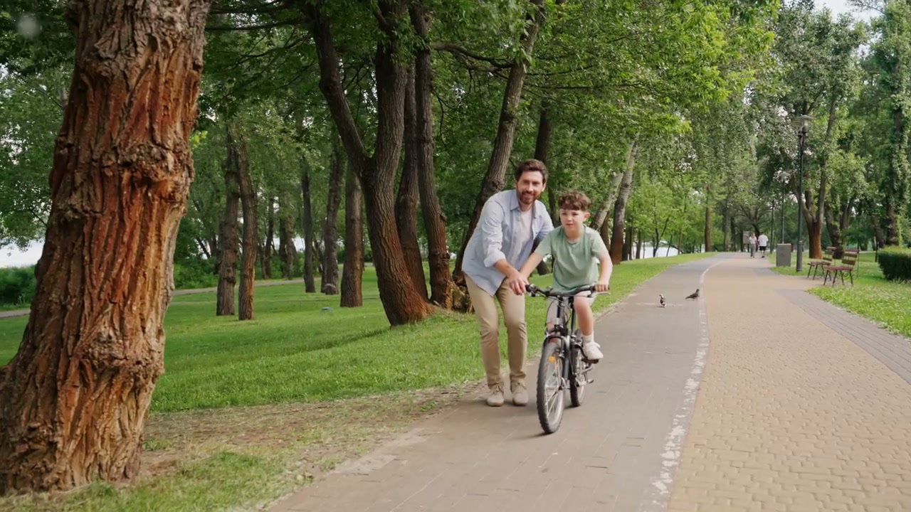 Father Teaches Son to Ride Bike in Park