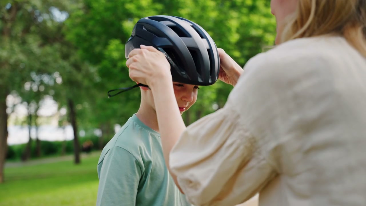 Mother Puts Helmet on Boy in Park