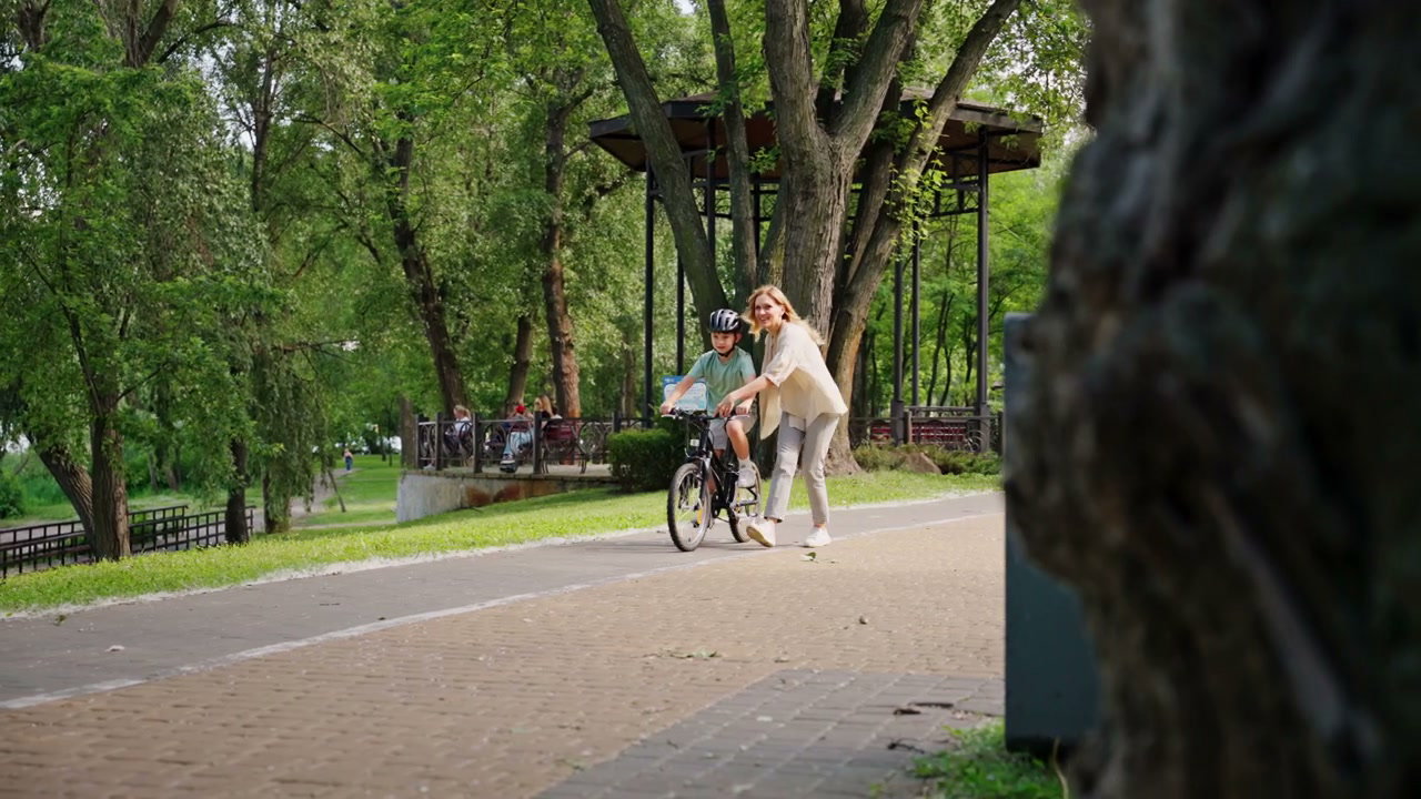 Mother Teaching Son to Ride Bike in Park