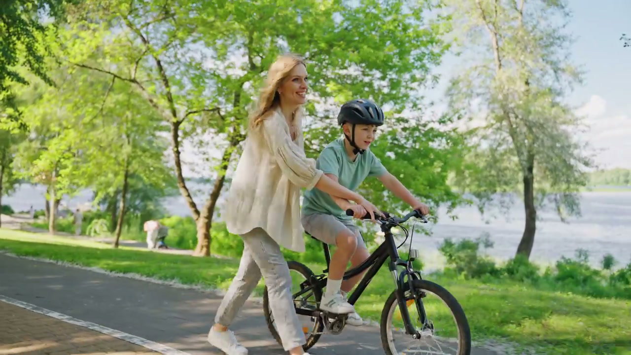 Mother Teaches Son to Ride Bike in Park