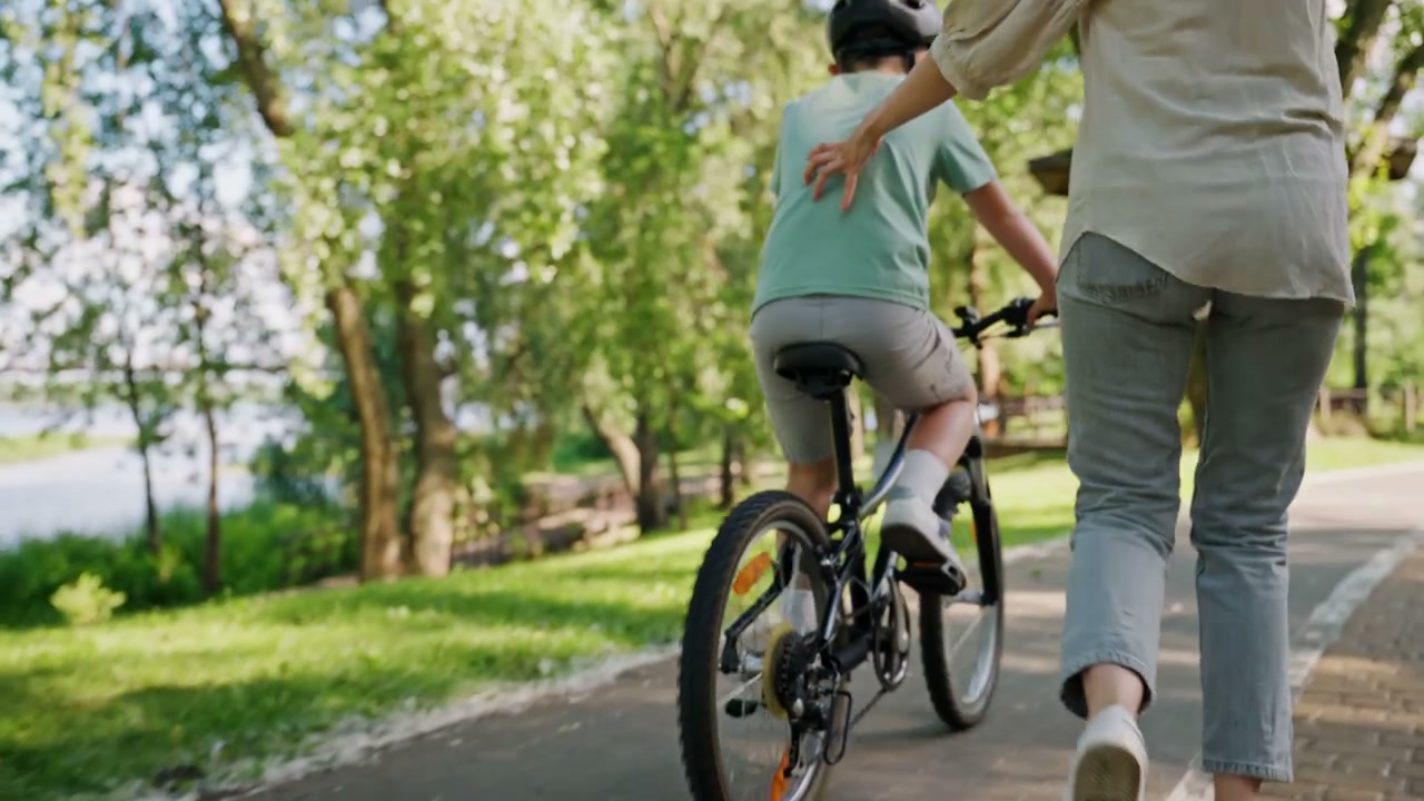 Woman Teaching Boy to Ride Bicycle
