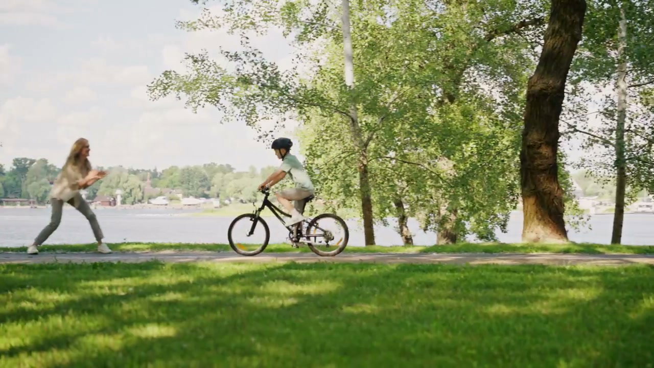 Mother Teaching Son to Ride Bike in Park