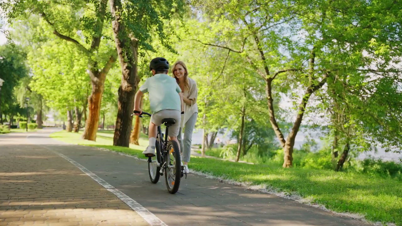 Boy Learning to Ride Bike with Mother in Park