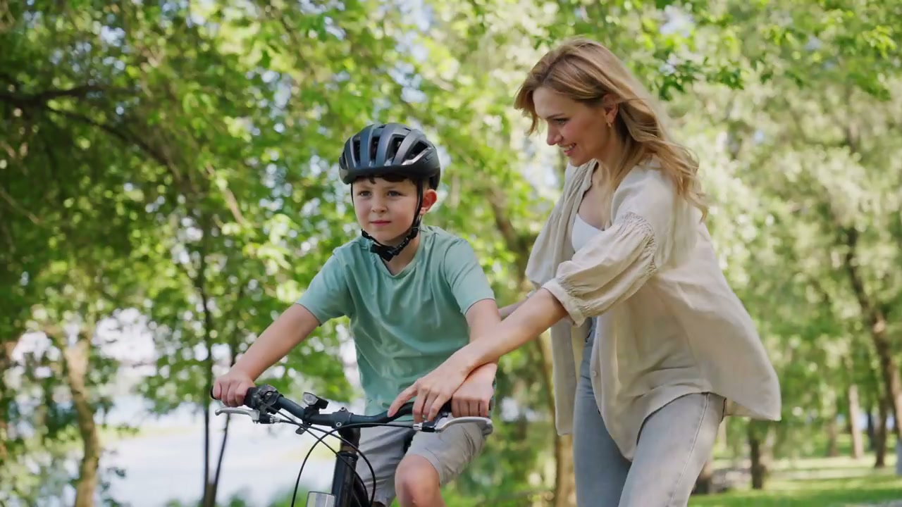 Mother Teaching Son to Ride a Bicycle in a Park