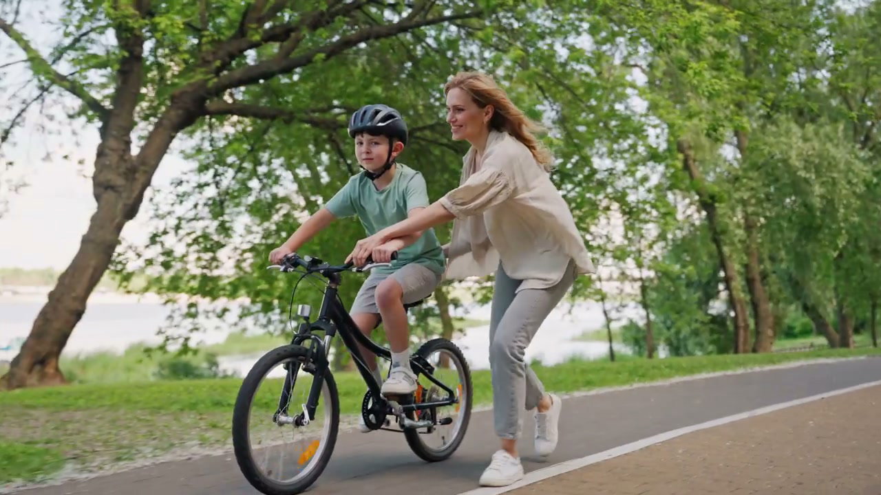 Mother Teaches Son to Ride Bike in Park