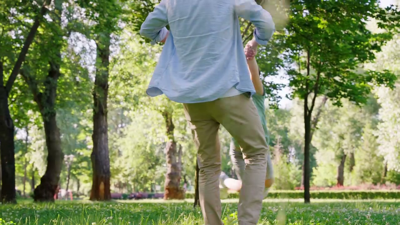 Father Swinging Son in Park