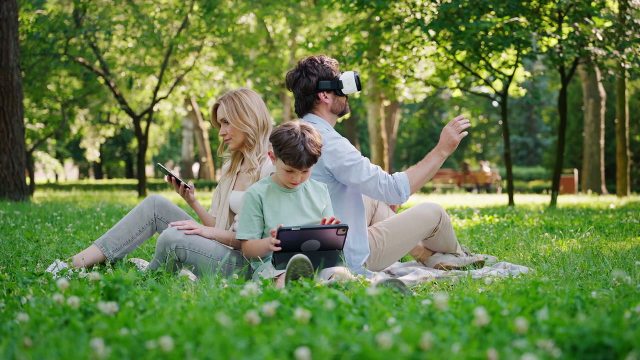 Family Using Digital Devices in Park