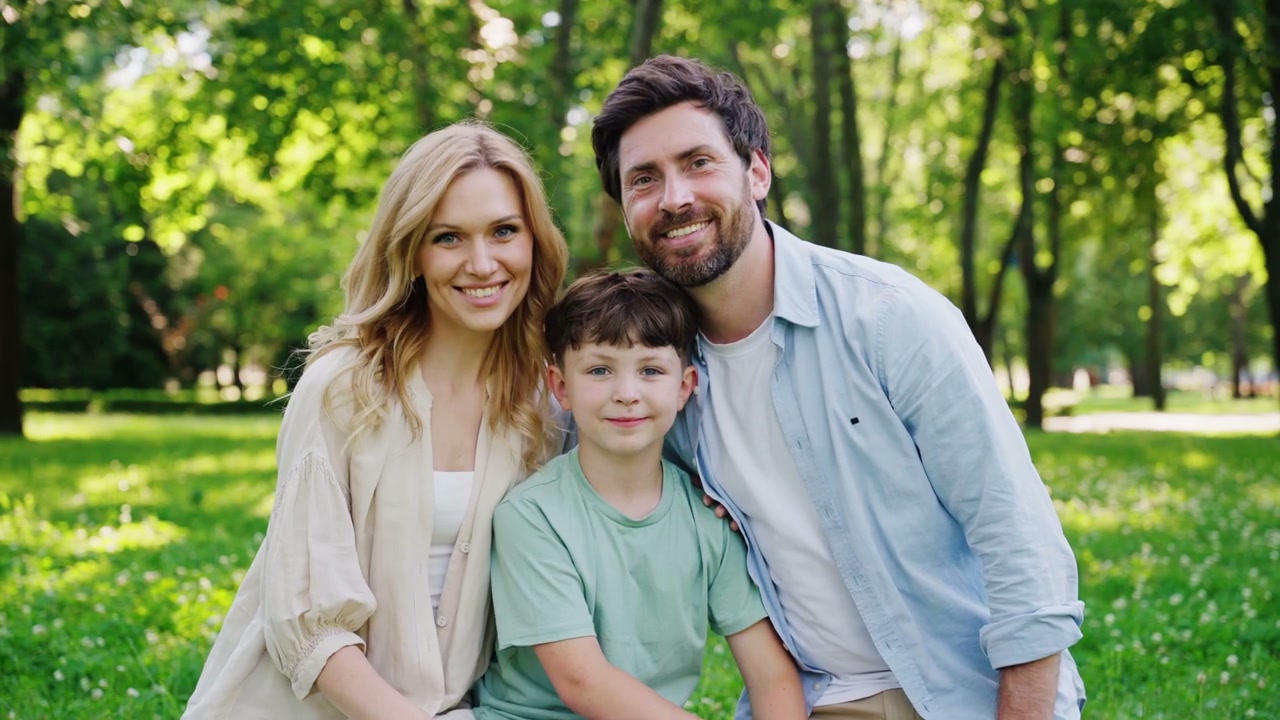Happy Family Smiling at Camera in Park