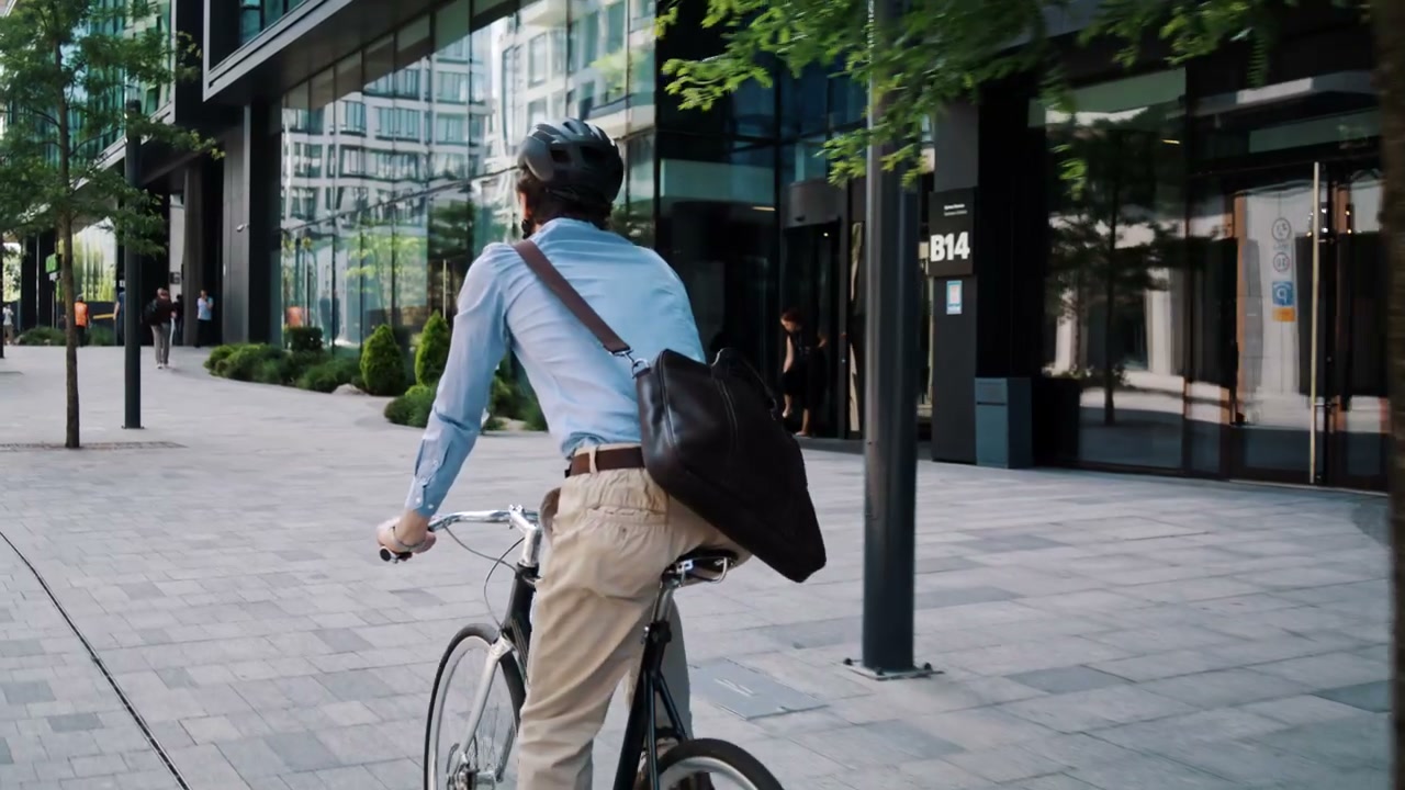 Businessman Cycling Through Modern City Street