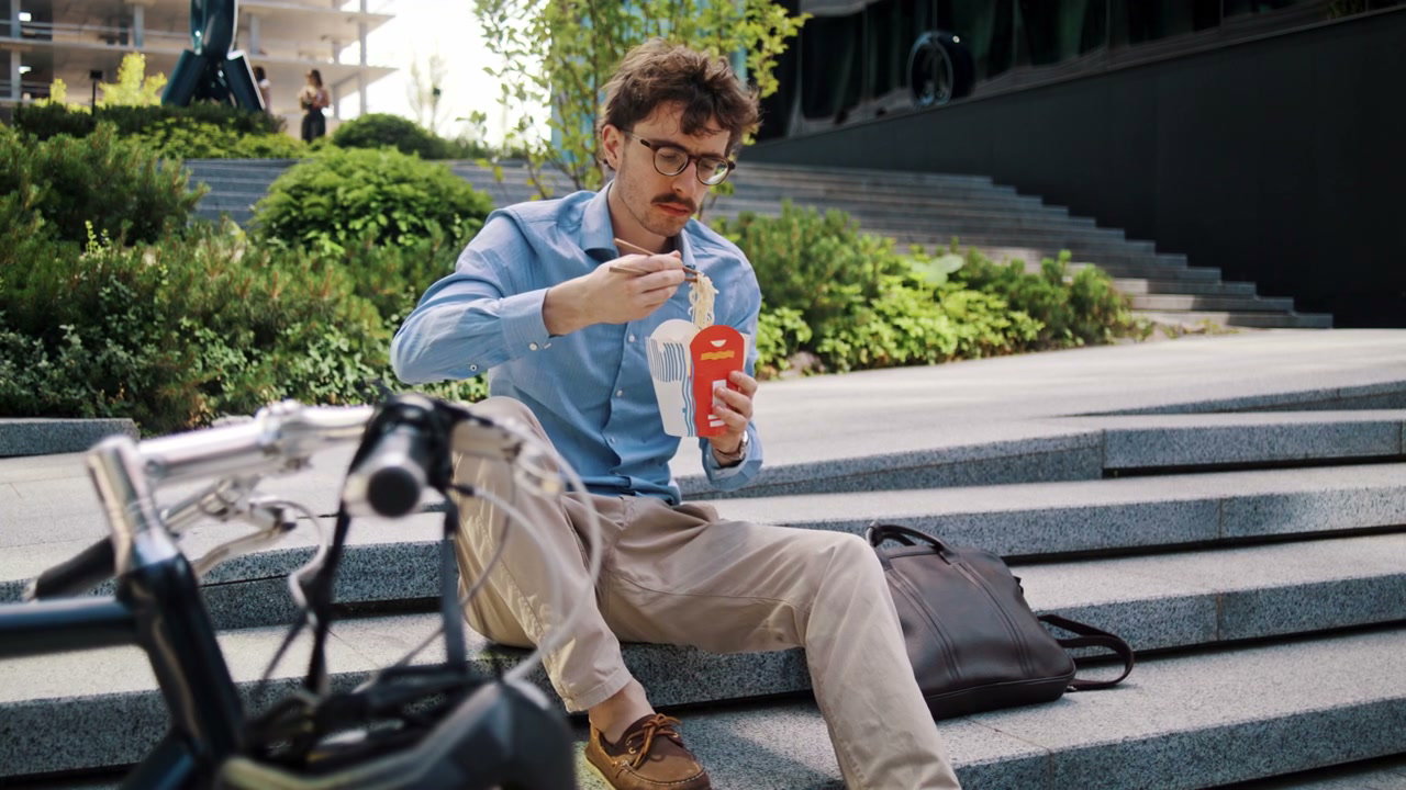 Man Eats Noodles on City Steps with Bike