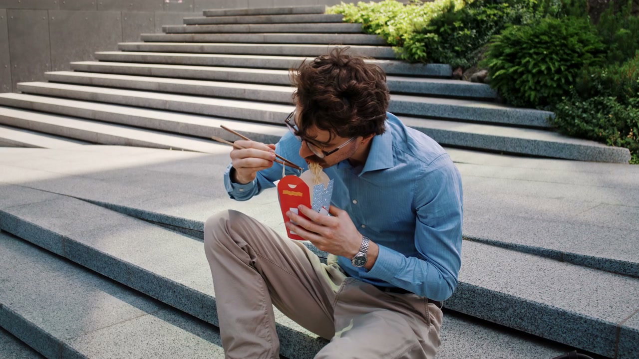 Young Man Eating Noodles Outdoors