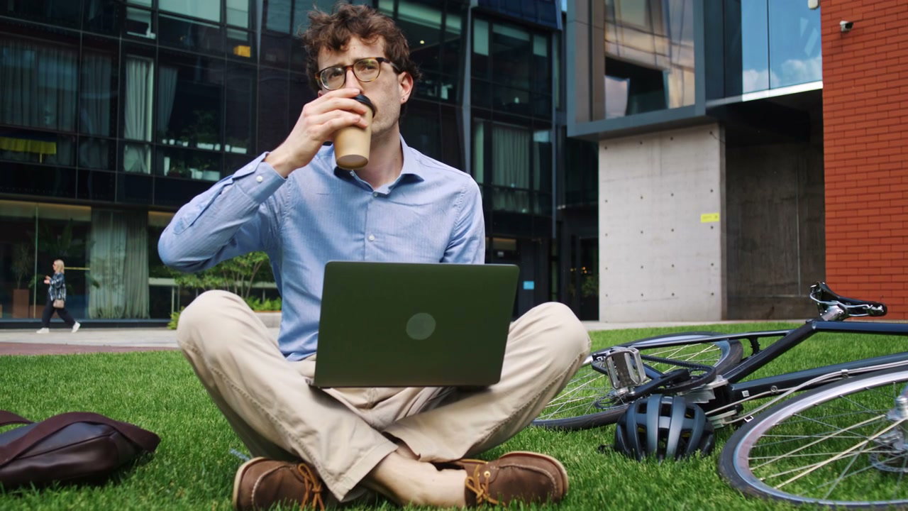 Man Working on Laptop and Drinking Coffee Outdoors