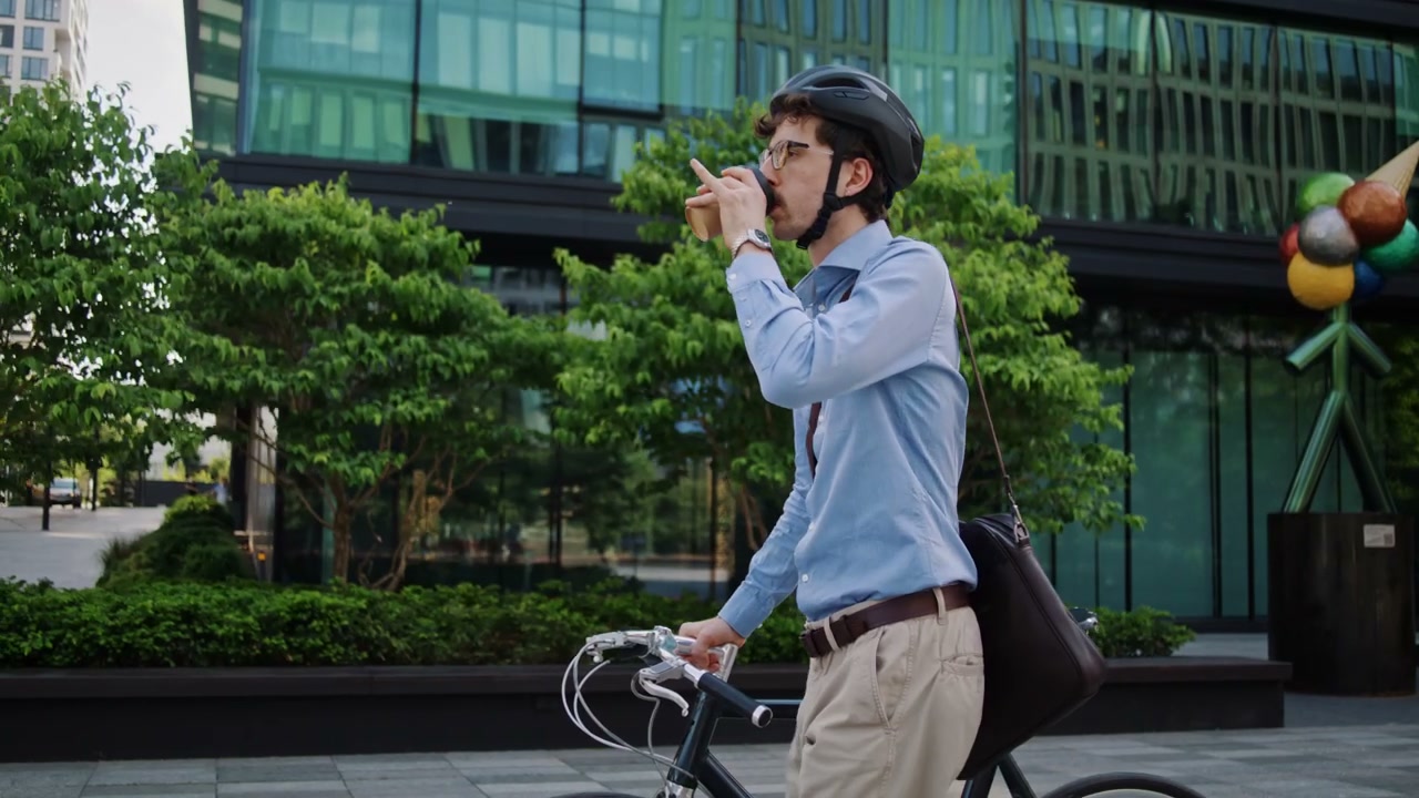 Man Walking Bike and Drinking Coffee in City