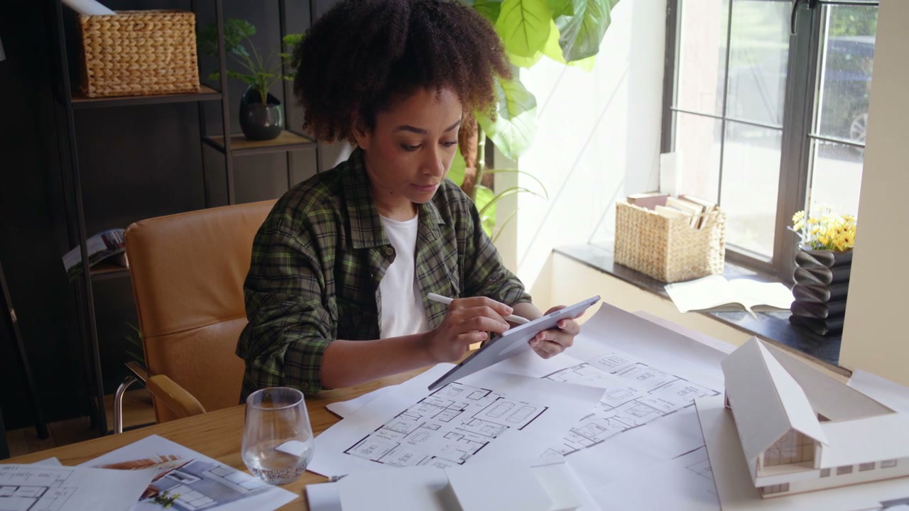 Female Architect Working On Blueprints With Tablet