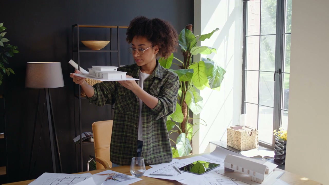 Young Woman Architect Examining House Model