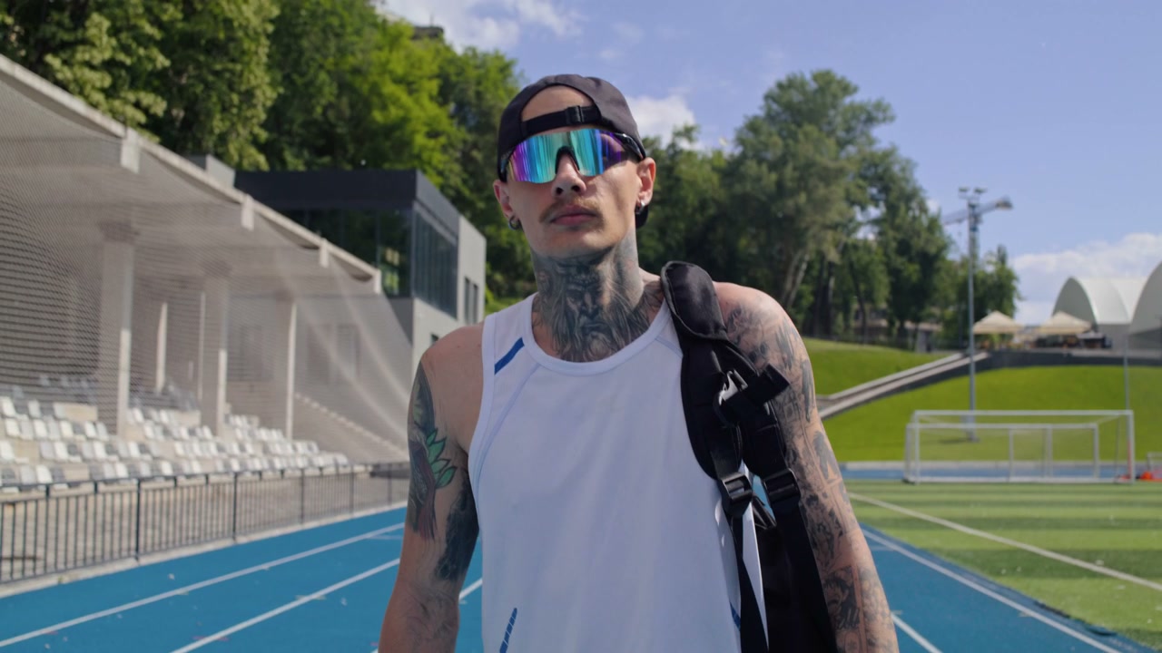Tattooed Man Walking on Track in Stadium