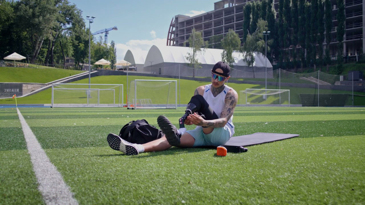 Adaptive Athlete Adjusting Prosthetic Leg on Field