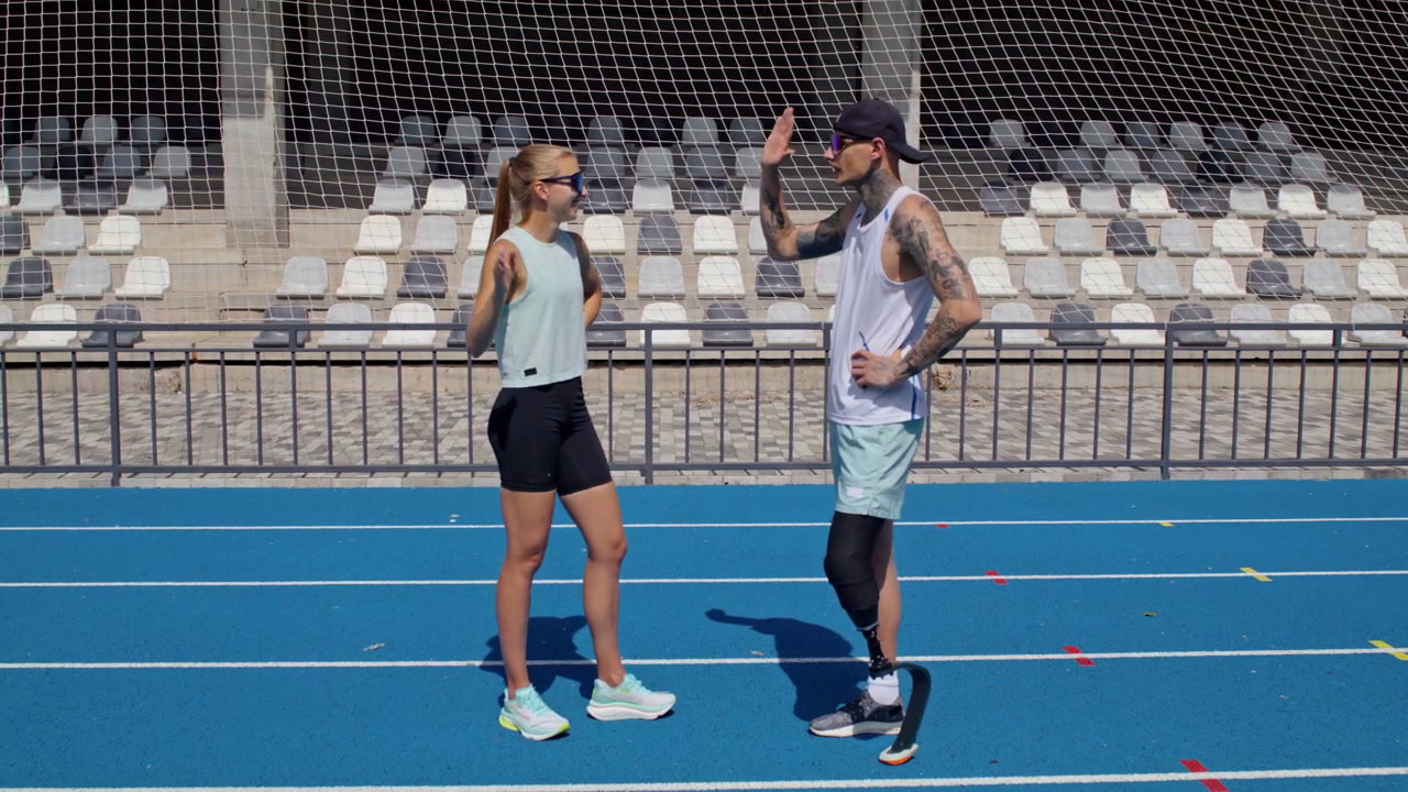 Man with Prosthetic Leg High Fives Woman on Track