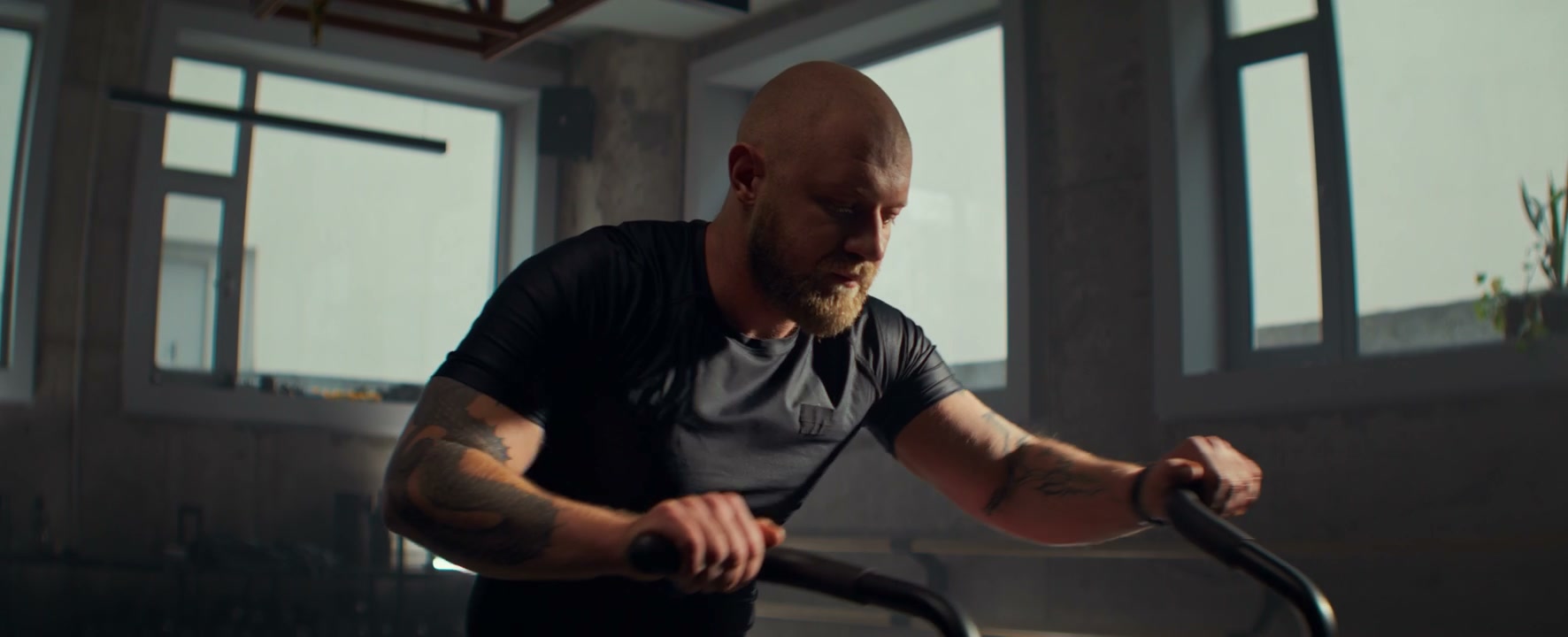 Bald Man Training on Exercise Bike in Gym